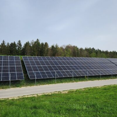 Solaranlagen auf einem Wall, vor denen ein Weg entlang führt