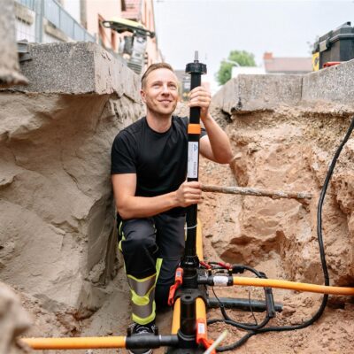 Ein Mitarbeiter der ThügaNETZE steht in einer Baustelle und verlegt unterirdisch verlaufende Kabel