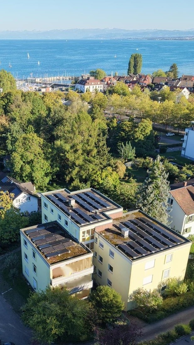 Blick von oben auf Ein- und Mehrfamilienhäusern mit PV-Anlagen in Ufernähe